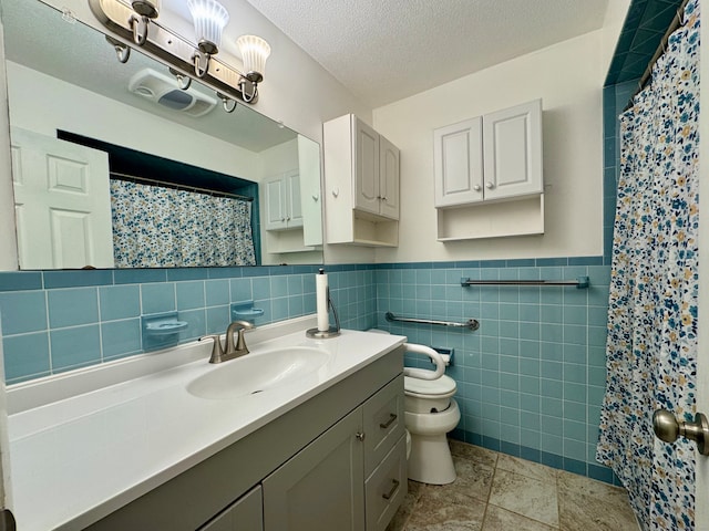 bathroom featuring a textured ceiling, vanity, tile walls, tile patterned flooring, and toilet