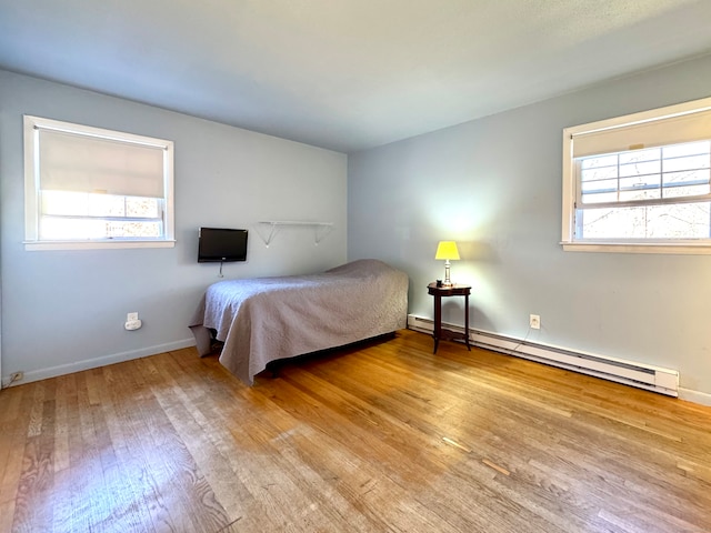 unfurnished bedroom featuring a baseboard radiator, multiple windows, and light hardwood / wood-style floors