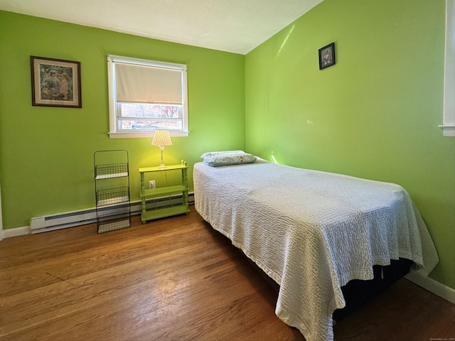 bedroom featuring hardwood / wood-style flooring and a baseboard heating unit