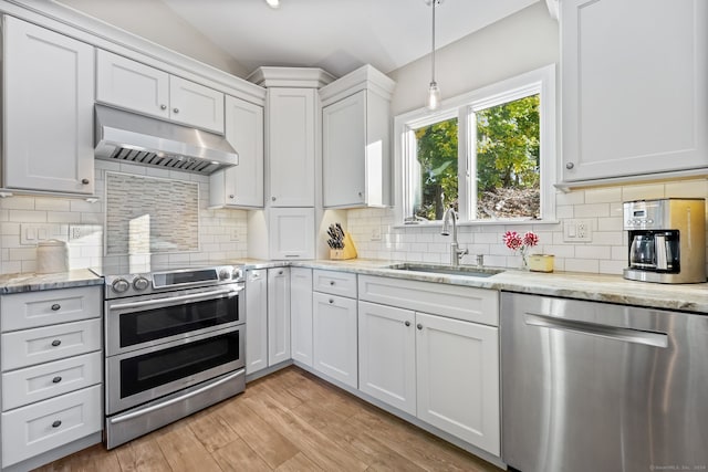 kitchen featuring decorative backsplash, stainless steel appliances, sink, white cabinets, and light hardwood / wood-style floors