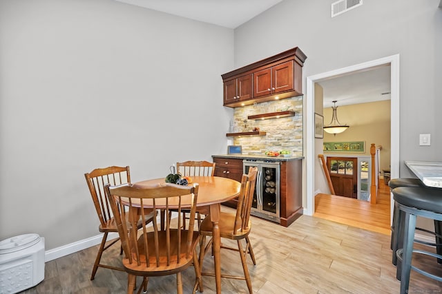 dining area with light hardwood / wood-style flooring and beverage cooler