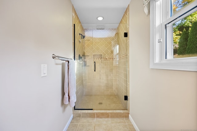 bathroom with a shower with door and tile patterned floors