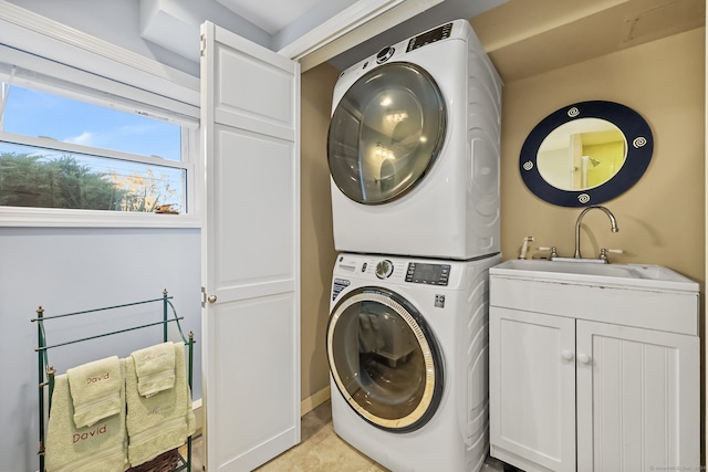 washroom featuring cabinets, stacked washer / drying machine, and sink