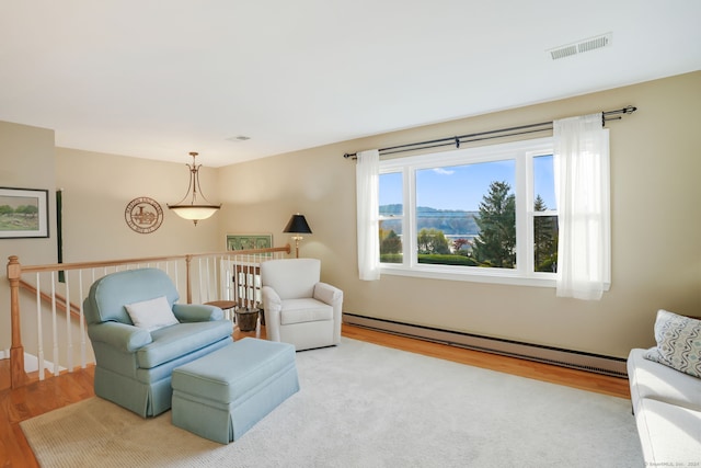 sitting room featuring a baseboard heating unit and wood-type flooring