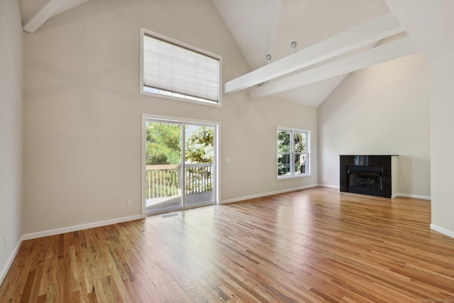 unfurnished living room with high vaulted ceiling, a tile fireplace, and light hardwood / wood-style floors