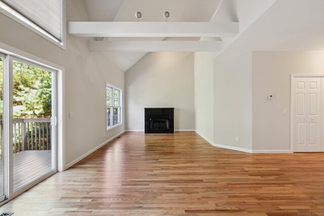 unfurnished living room featuring high vaulted ceiling, beamed ceiling, and light wood-type flooring