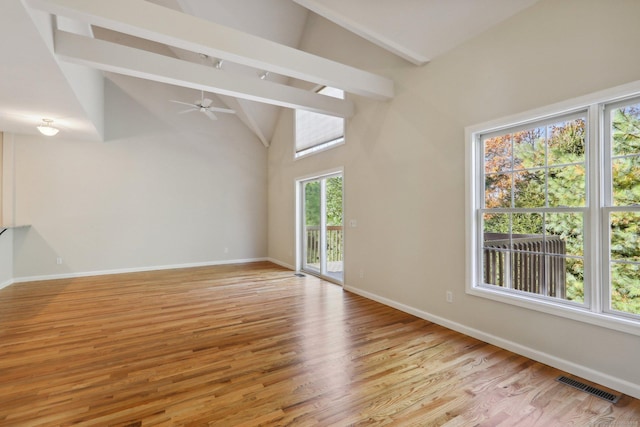 empty room with ceiling fan, high vaulted ceiling, beam ceiling, and light hardwood / wood-style flooring