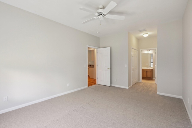 unfurnished bedroom featuring light carpet, connected bathroom, and ceiling fan