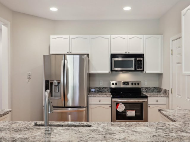 kitchen with white cabinetry, sink, light stone counters, and stainless steel appliances