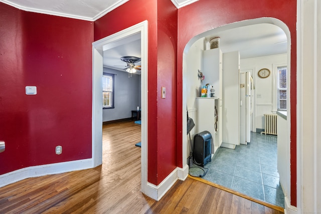 hall with ornamental molding, radiator, and wood-type flooring