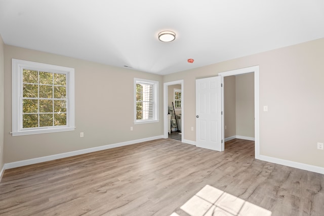 unfurnished bedroom featuring multiple windows and light hardwood / wood-style floors