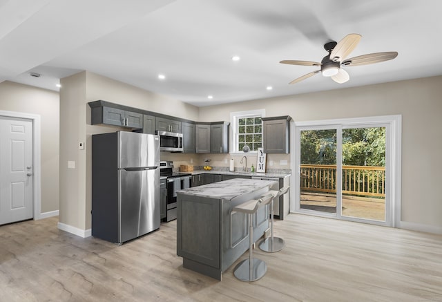 kitchen featuring appliances with stainless steel finishes, light hardwood / wood-style flooring, a center island, and ceiling fan