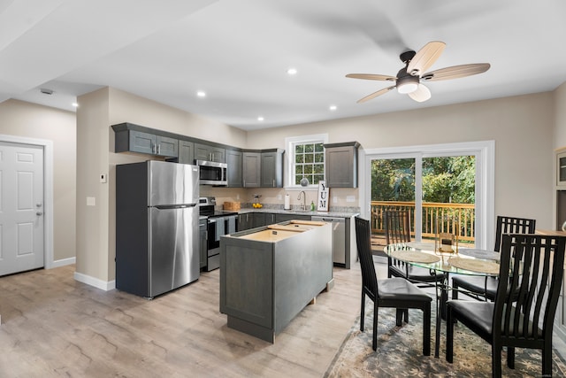 kitchen featuring a center island, ceiling fan, light hardwood / wood-style floors, stainless steel appliances, and gray cabinets