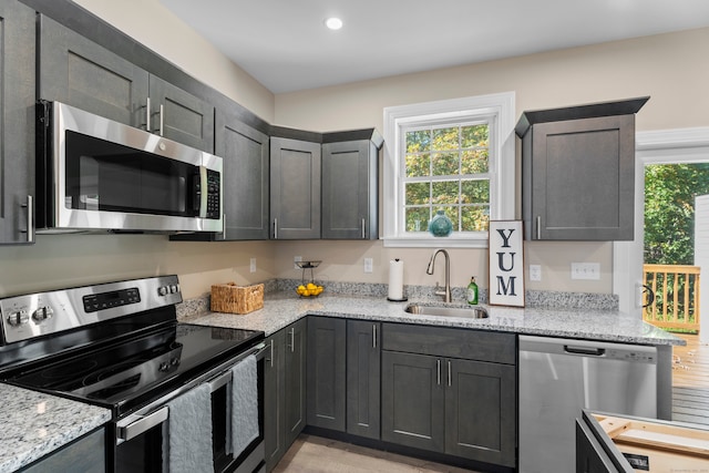 kitchen with light stone counters, appliances with stainless steel finishes, and sink