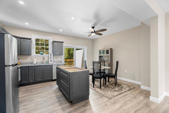 kitchen with stainless steel appliances, sink, light wood-type flooring, and a kitchen island