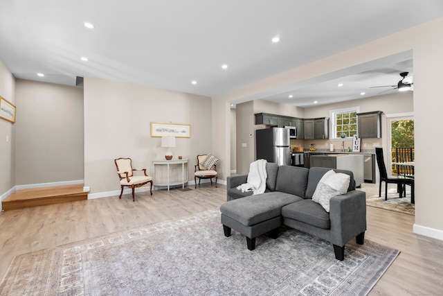 living room with ceiling fan, sink, and light wood-type flooring