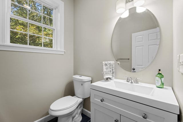 half bath featuring baseboards, toilet, and vanity