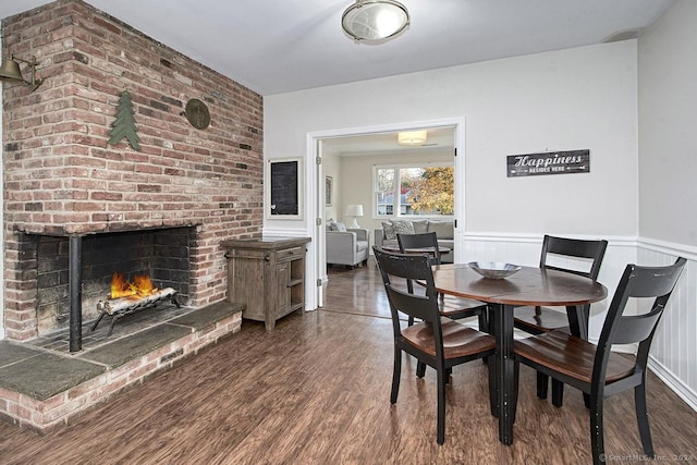 dining space featuring dark hardwood / wood-style flooring and a brick fireplace