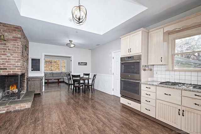 kitchen with a fireplace, a healthy amount of sunlight, stainless steel appliances, and tasteful backsplash