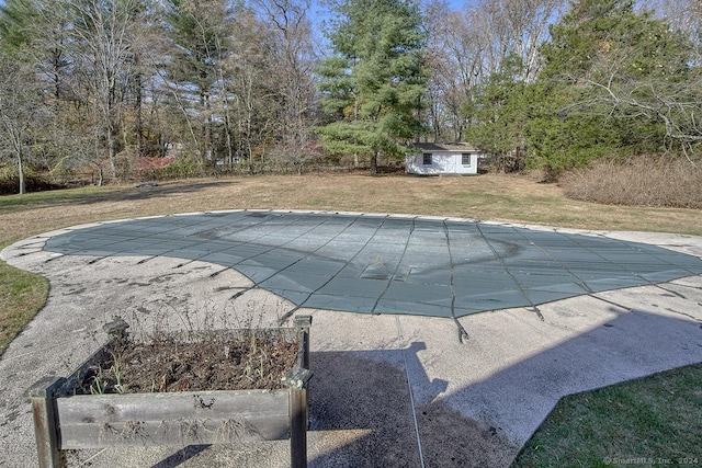 view of pool with a lawn, a patio area, and a storage shed