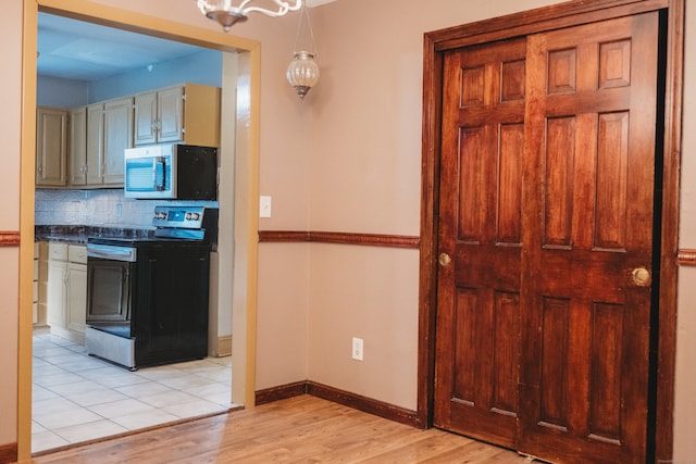 kitchen featuring backsplash, electric range oven, hanging light fixtures, and light hardwood / wood-style floors