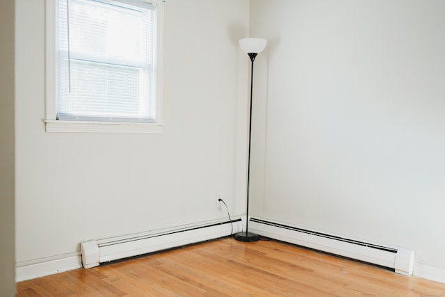 empty room featuring baseboard heating and hardwood / wood-style flooring