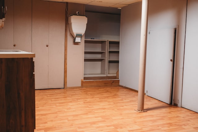 interior space featuring a drop ceiling, sink, and light wood-type flooring