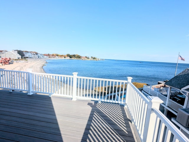 wooden terrace featuring a water view and a beach view