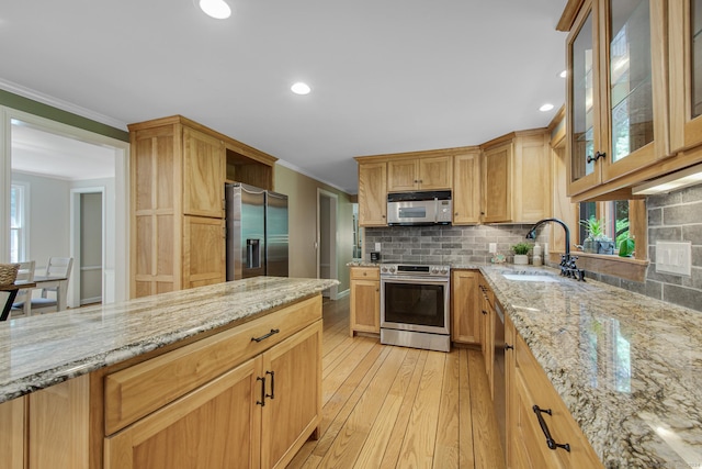 kitchen with light stone countertops, appliances with stainless steel finishes, light hardwood / wood-style flooring, and sink