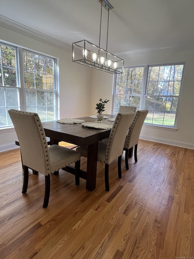 dining space with light wood-type flooring and ornamental molding