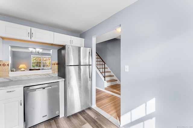 kitchen with decorative backsplash, dark wood-type flooring, white cabinets, a notable chandelier, and appliances with stainless steel finishes