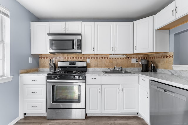 kitchen with sink, appliances with stainless steel finishes, white cabinetry, and tasteful backsplash