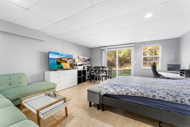 bedroom with access to exterior, a paneled ceiling, and light tile patterned floors