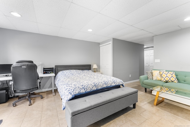 tiled bedroom with a closet and a paneled ceiling