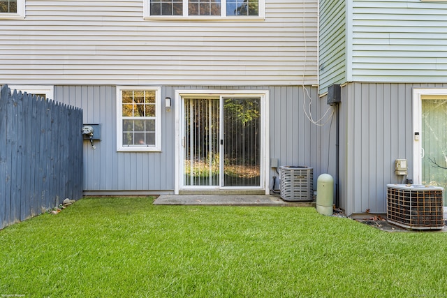 view of exterior entry featuring a lawn and central AC unit