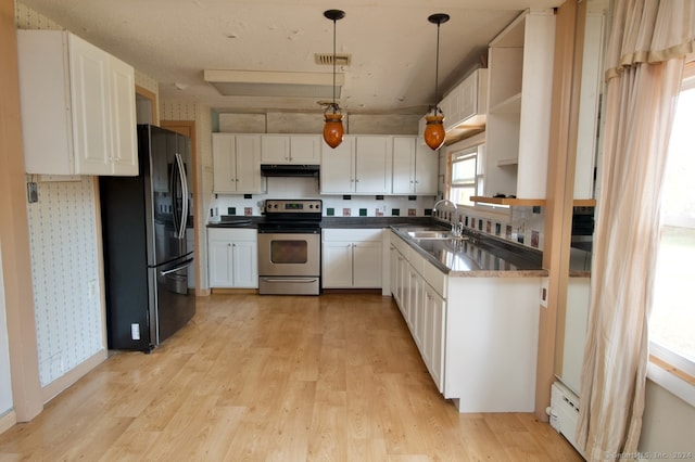 kitchen with appliances with stainless steel finishes, white cabinets, hanging light fixtures, and light wood-type flooring