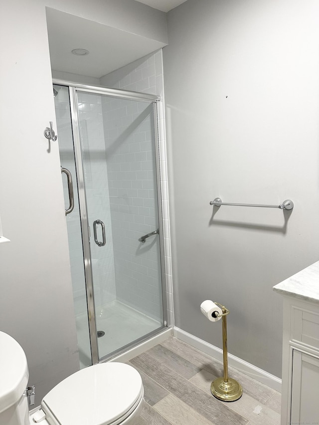 bathroom with hardwood / wood-style floors, vanity, a shower with shower door, and toilet