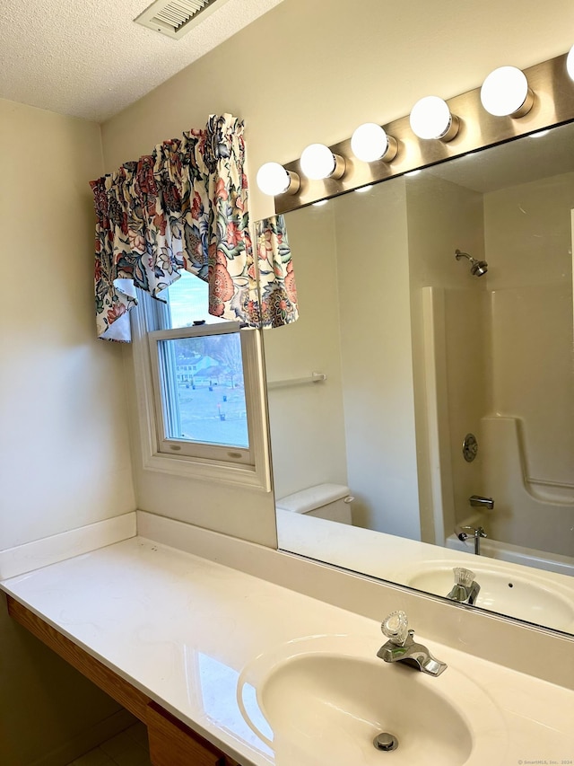 full bathroom with shower / washtub combination, vanity, a textured ceiling, and toilet