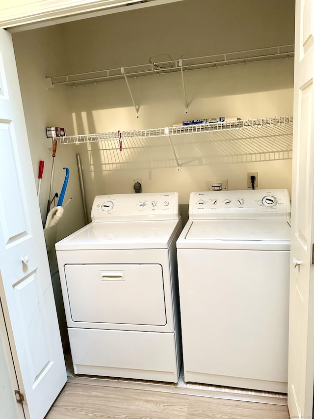 laundry area with light hardwood / wood-style floors and washer and clothes dryer