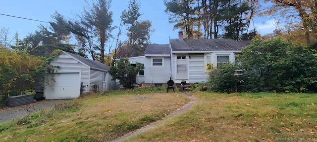 back of property with an outbuilding, a yard, and a garage