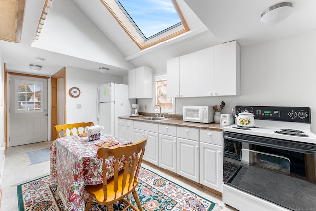 kitchen featuring sink, light tile patterned floors, lofted ceiling with skylight, white cabinetry, and white appliances