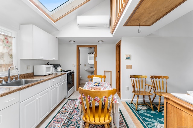 kitchen featuring an AC wall unit, sink, lofted ceiling with skylight, white cabinetry, and white appliances