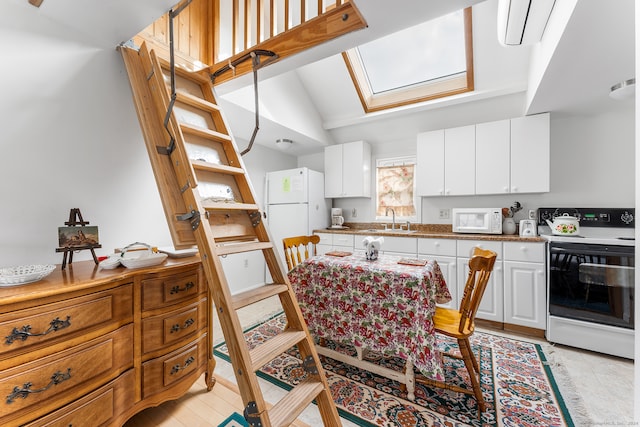 kitchen featuring white cabinets, light tile patterned flooring, vaulted ceiling with skylight, sink, and white appliances