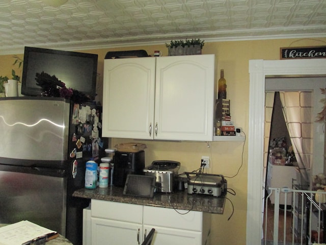 kitchen with white cabinetry, crown molding, and stainless steel refrigerator