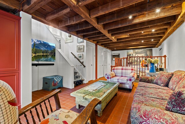 living room with beamed ceiling, dark tile patterned flooring, and wooden ceiling