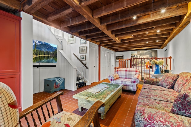 living area with stairs, dark tile patterned flooring, beamed ceiling, and wooden ceiling