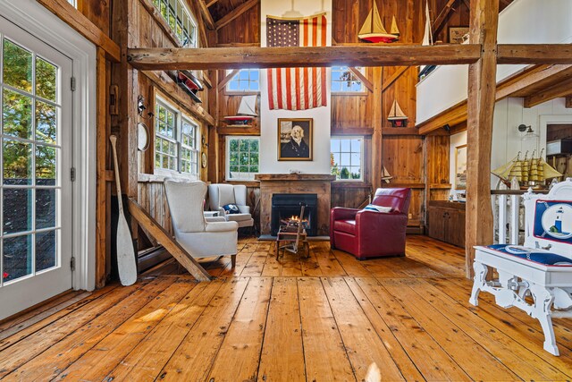 living area featuring light wood-style floors, a lit fireplace, a high ceiling, and plenty of natural light