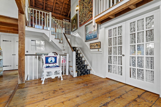 interior space featuring a towering ceiling, wood ceiling, wood finished floors, and french doors