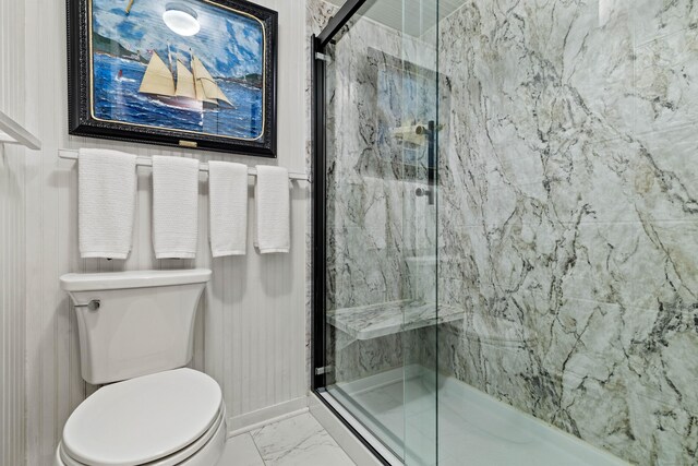 full bathroom with toilet, marble finish floor, a marble finish shower, and baseboards