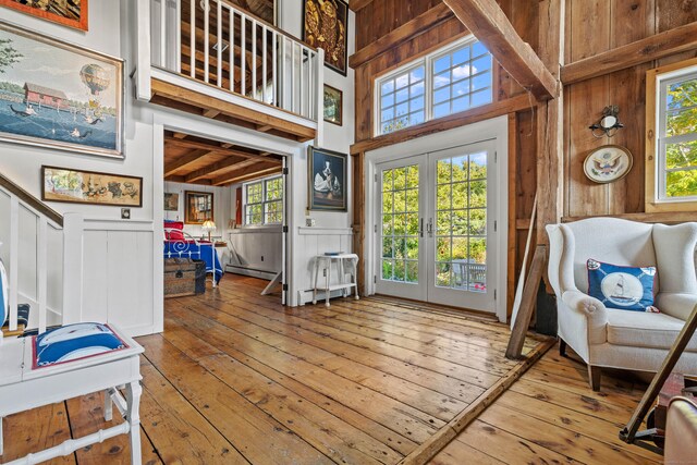 interior space with hardwood / wood-style flooring, a towering ceiling, french doors, and a baseboard heating unit